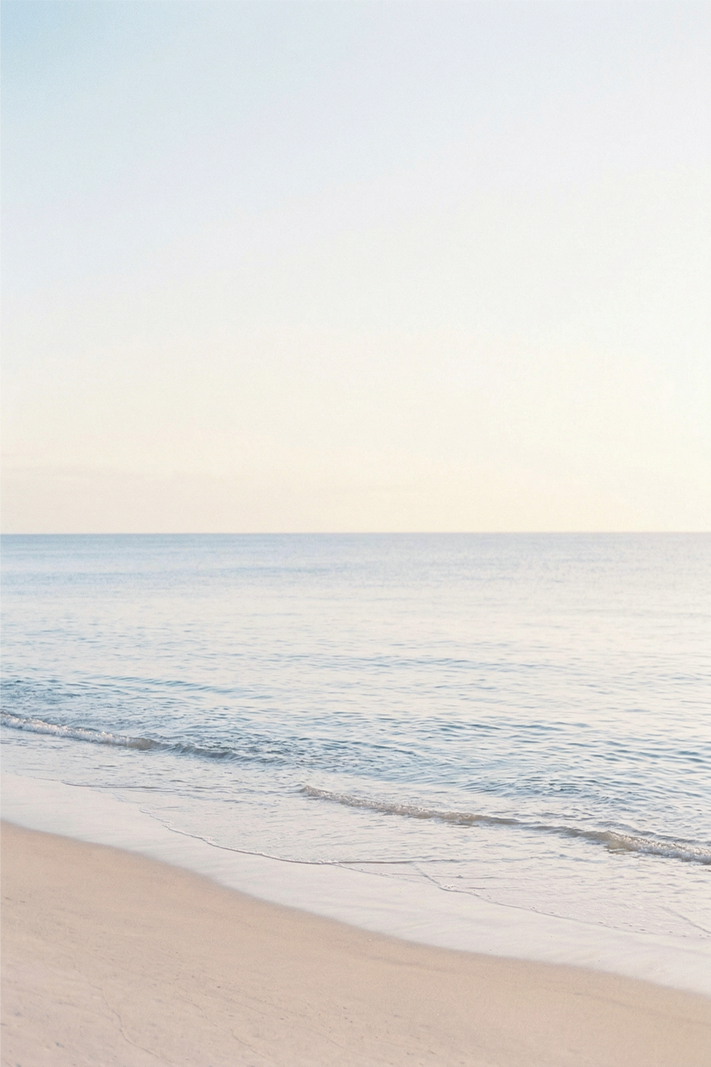 Ruhiges Meer und Sandstrand in Pastellfarben am Morgen